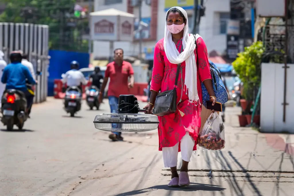 Una mujer carga con un ventilador comprado en un mercado en un día de altas temperaturas en Guwahati.