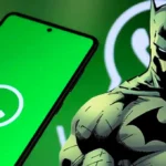 Batman junto a un teléfono Android con la app de WhatsApp abierta en pantalla, sobre un fondo verde con el logo de WhatsApp.