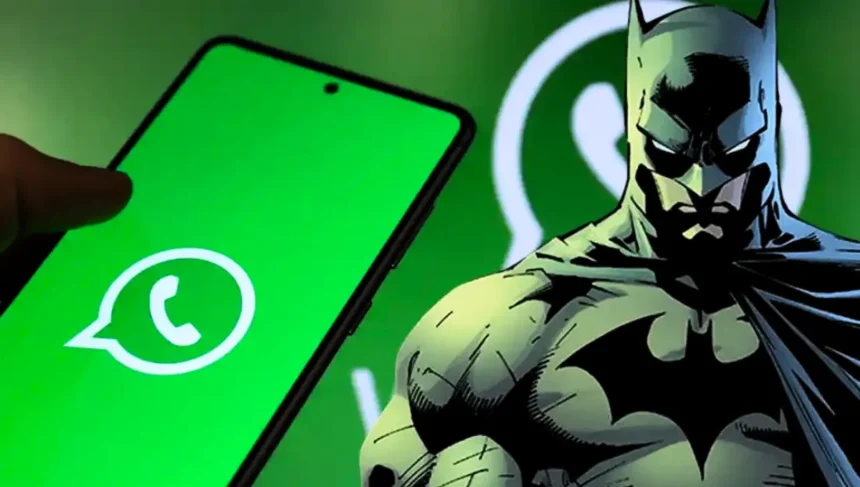 Batman junto a un teléfono Android con la app de WhatsApp abierta en pantalla, sobre un fondo verde con el logo de WhatsApp.