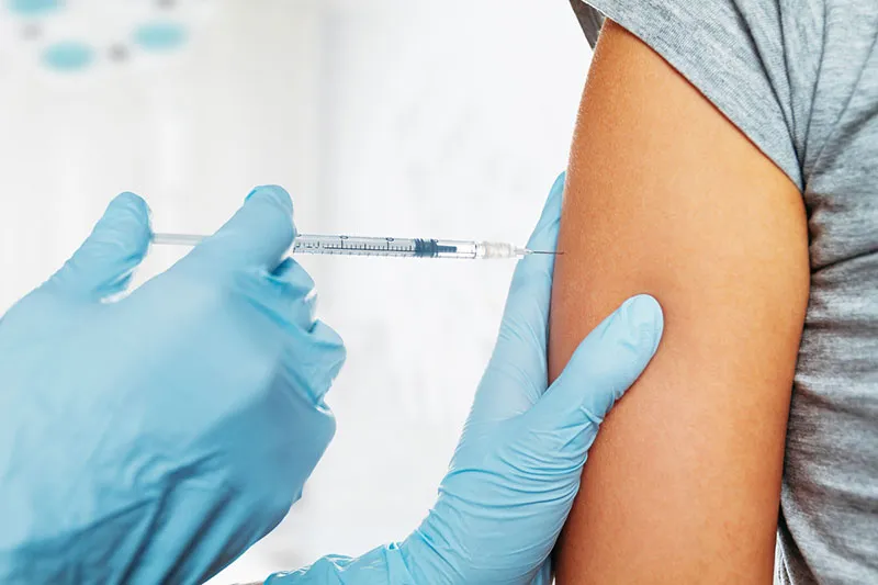 Vacunación en el brazo con una inyección intramuscular administrada por un profesional con guantes médicos.