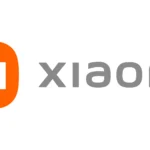Logotipo oficial de Xiaomi con fondo negro, ícono naranja con las letras “Mi” en blanco y el nombre de la marca en gris.