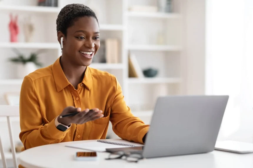 Profesional sonriente trabajando en remoto con laptop y auriculares, símbolo de bienestar laboral y cultura corporativa positiva en empresas modernas.