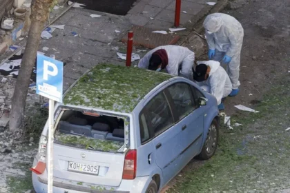 Investigadores forenses inspeccionan un auto cubierto de vidrios rotos tras una explosión en una calle de Salónica, Grecia.