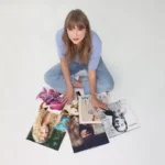 Taylor Swift sentada en el suelo rodeada de portadas de sus primeros seis discos recuperados, simbolizando su victoria artística en 2025.